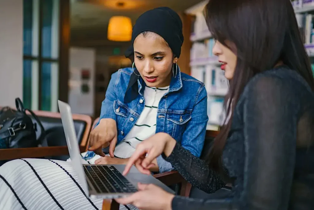 Women looking and pointing to a laptop during a meeting.