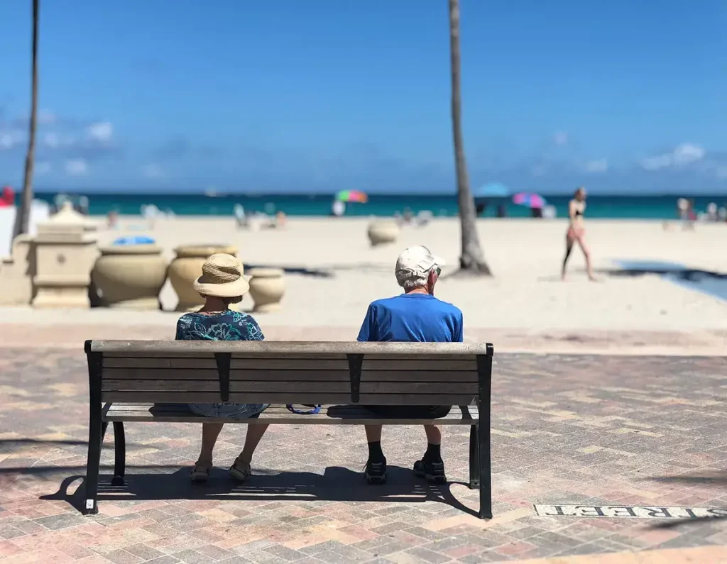 Seniors sitting on a beach looking at a beach.