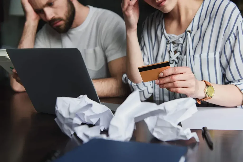 Couple looking stressed about money and holding a credit card.