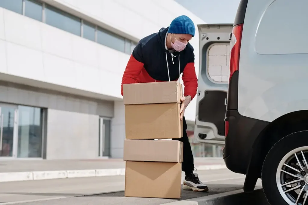 Person in a mask loading boxes into a van.