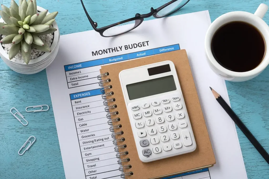 A print out of a monthly budget covered by a notebook and calculator.