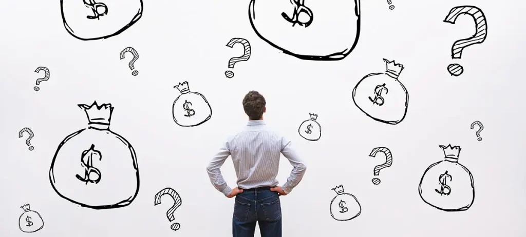 Back of a man looking at drawings of money bags and question marks.