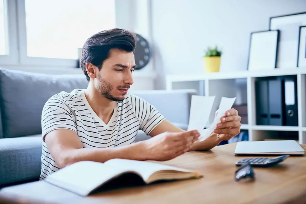 Man looking at receipts at a coffee table.