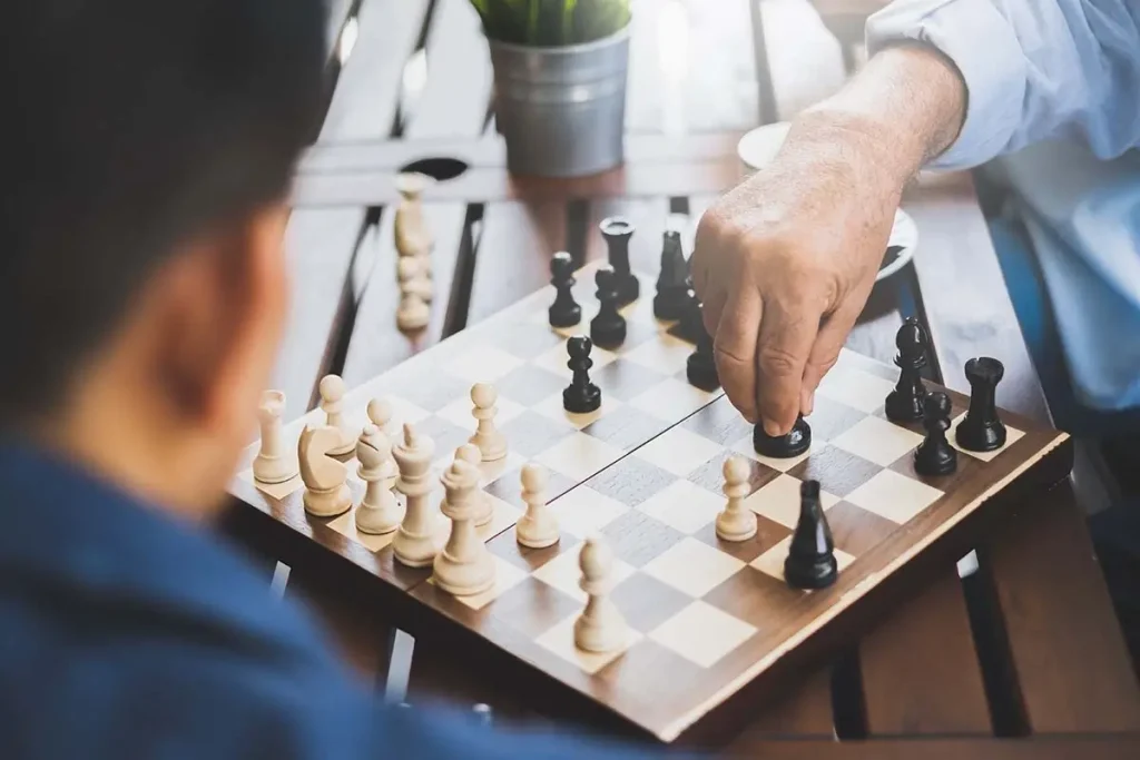 People playing chess at a picnic table.