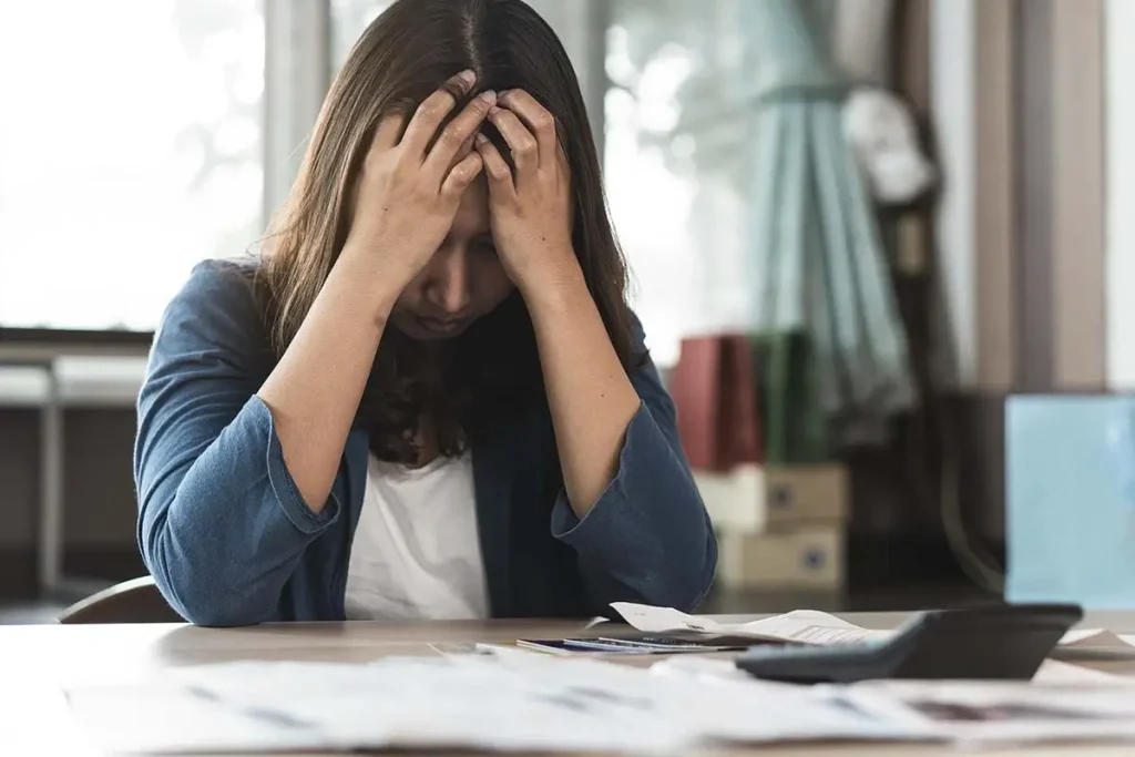 A business owner looking stressed while looking at credit cards and receipts.