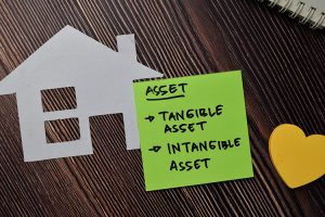 Tangible Asset and Intangible Asset written on sticky note isolated on wooden table