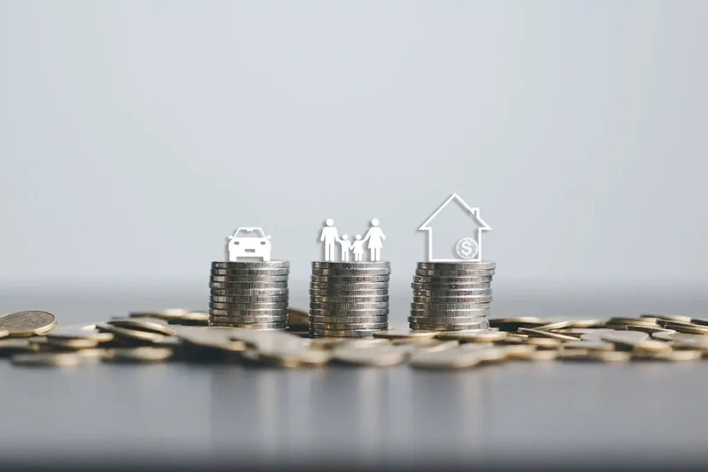 Three stacks of coins with icons of a car, a family, and a house on top.