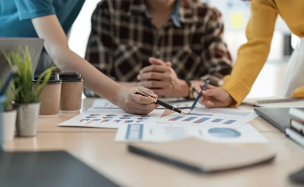 Three employees reviewing graphs at a meeting.