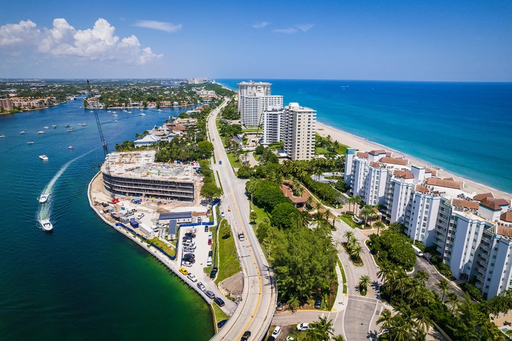 City of Naples Florida Aerial view. Buildings along the coastline, cars driving on the roads and boats in the water.