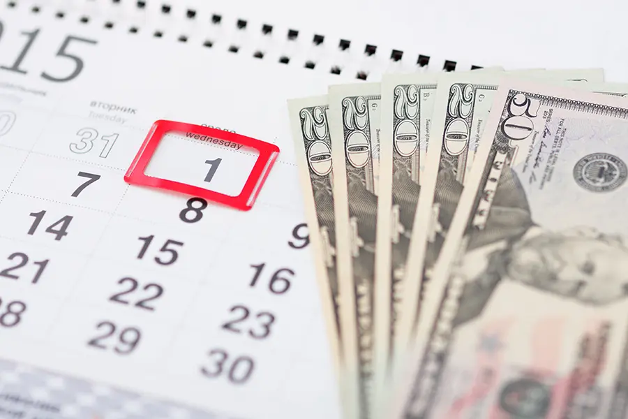 Money placed on top of a calendar with the date quarterly tax returns are due highlighted