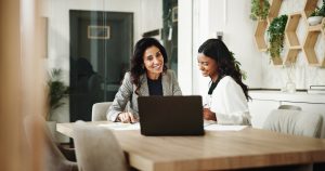 Woman and accountant discussing feedback in meeting space with laptop.